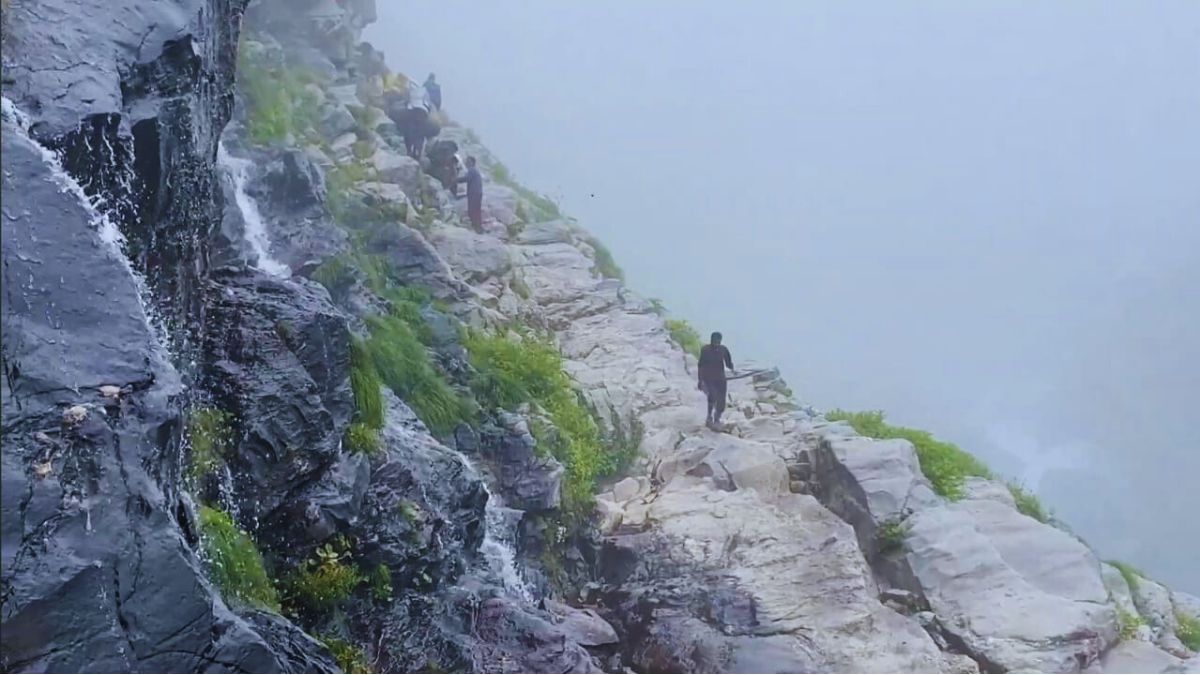 Trekker walking along Hampta Pass trail with Himalayan backdrop
