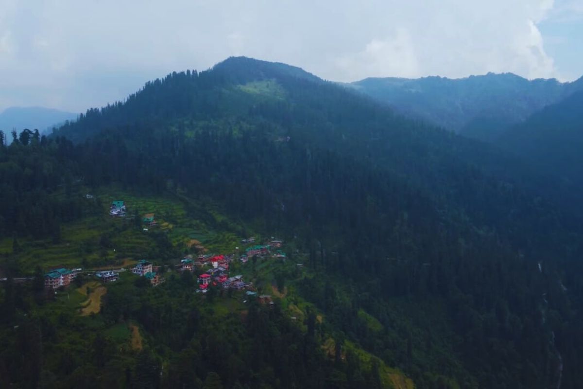Morning mist covering Shoja and Gushaini villages surrounded by dense green forests in Tirthan Valley, Himachal Pradesh 
