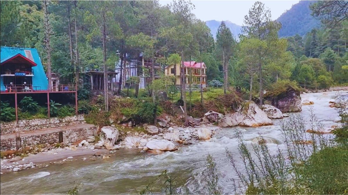 “Hiker near waterfall in Tirthan Valley during rain”