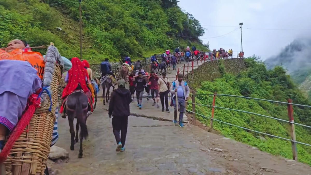 Pilgrims walking with ponchos in rain toward Kedarnath